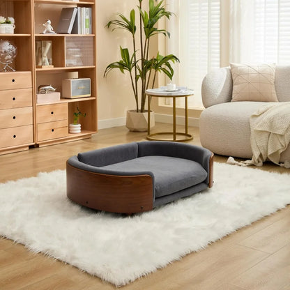 Modern sofa style pet bed designed for dogs, shown in a home living space with a cushioned sleeping surface and supportive wraparound sides for everyday comfort