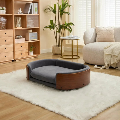 Modern sofa style pet bed designed for dogs, shown in a home living space with a cushioned sleeping surface and supportive wraparound sides for everyday comfort