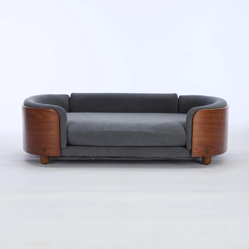 Modern sofa style pet bed designed for dogs, shown in a home living space with a cushioned sleeping surface and supportive wraparound sides for everyday comfort