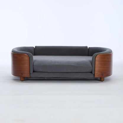 Modern sofa style pet bed designed for dogs, shown in a home living space with a cushioned sleeping surface and supportive wraparound sides for everyday comfort