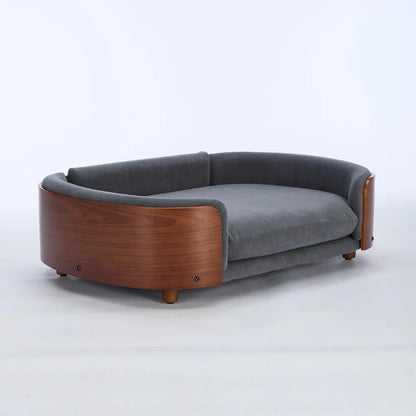 Modern sofa style pet bed designed for dogs, shown in a home living space with a cushioned sleeping surface and supportive wraparound sides for everyday comfort