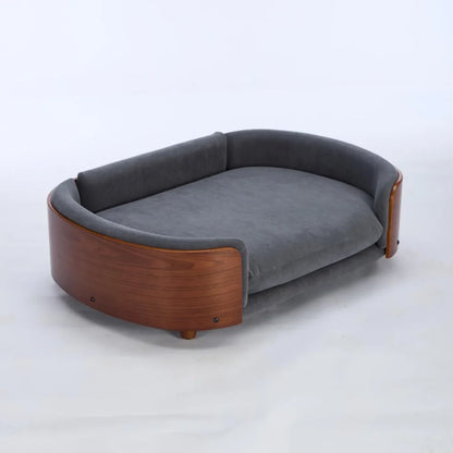 Modern sofa style pet bed designed for dogs, shown in a home living space with a cushioned sleeping surface and supportive wraparound sides for everyday comfort
