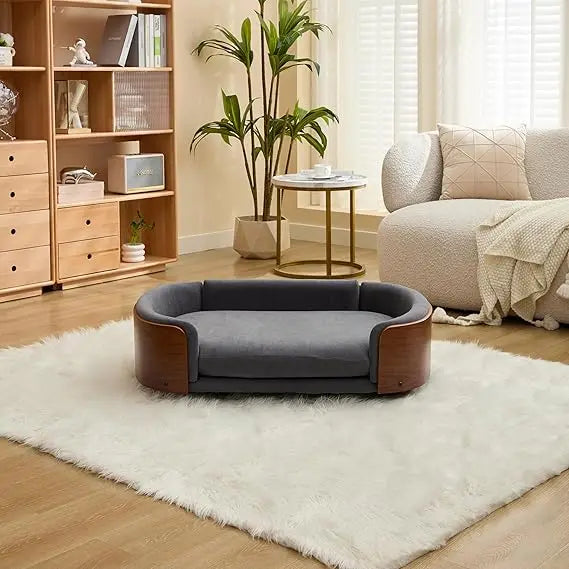 Modern sofa style pet bed designed for dogs, shown in a home living space with a cushioned sleeping surface and supportive wraparound sides for everyday comfort